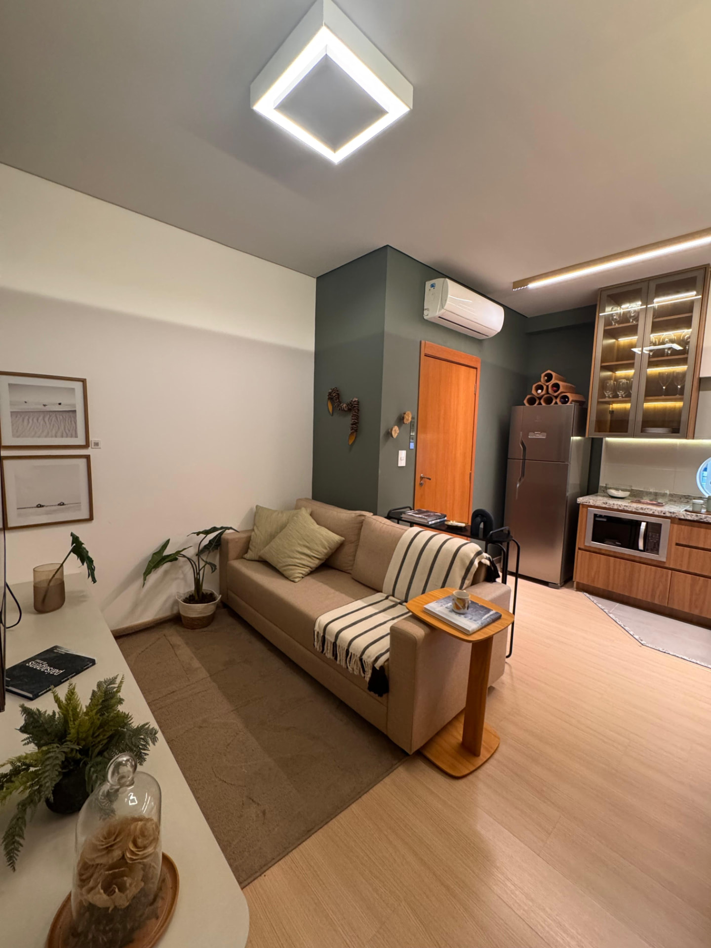 Sala de estar com sofá e cozinha integrada do apartamento decorado